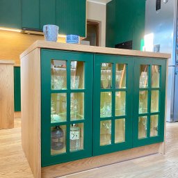 Livaro Meble - Zielona szafka z przeszklonymi drzwiczkami, podświetlona od wewnątrz, z ekspozycją szkła i alkoholi. Uzupełnienie aranżacji kuchni z zielonymi szafkami.