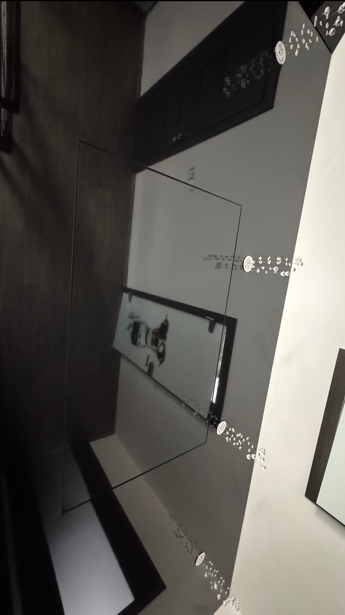 Błyszczący, czarny sufit z dekoracyjnymi kryształkami i lustrzanym odbiciem, tworzący nowoczesny i elegancki efekt wizualny w pomieszczeniu.