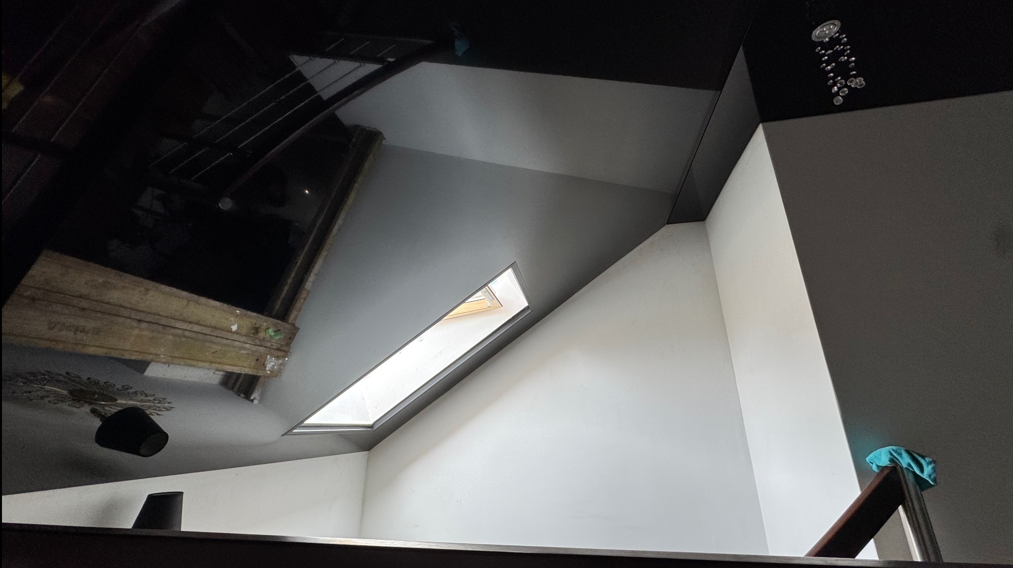 Nowoczesne wnętrze z czarnym połyskującym sufitem, oknem dachowym i minimalistycznym oświetleniem. Widok z dołu.