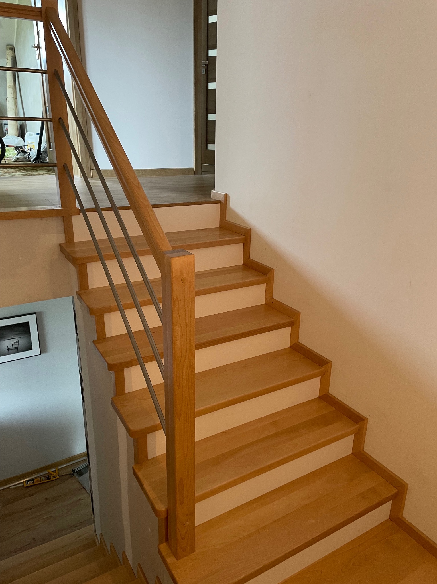 Jasne drewniane schody z metalową balustradą w nowoczesnym wnętrzu. Widok z góry, ukazujący detale wykończenia i naturalne światło. Minimalistyczny design.