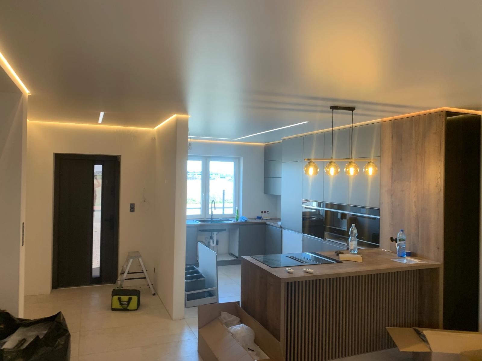 Nowoczesne oświetlenie LED sufitu i kuchni w trakcie wykańczania wnętrza. Widok na wyspę kuchenną w Poznaniu.