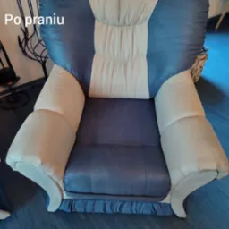 Wypielęgnowany, dwukolorowy fotel z miękką tapicerką po profesjonalnym czyszczeniu. Widoczne detale: dekoracyjne marszczenia u dołu, kontrastowe barwy.