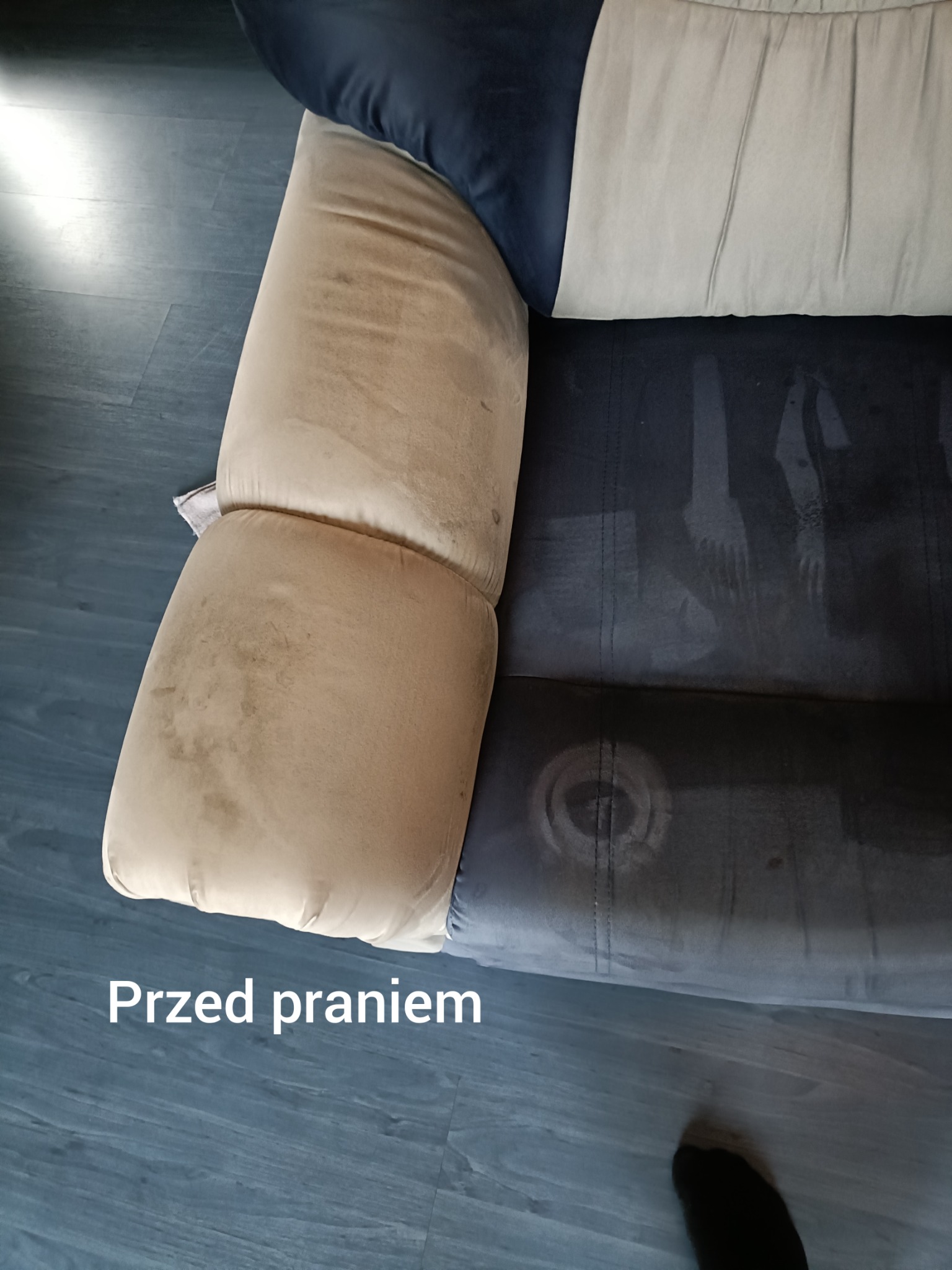 Tapicerka kanapy w odcieniach beżu i granatu, widoczna część wyprana, część zabrudzona. Ujęcie z góry, prezentujące efekt przed czyszczeniem.