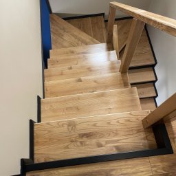 Stolarstwo Adam Pilch - Drewniane schody z czarnymi elementami wykończeniowymi, widok z góry, ukazujący naturalny rysunek drewna i solidną konstrukcję.