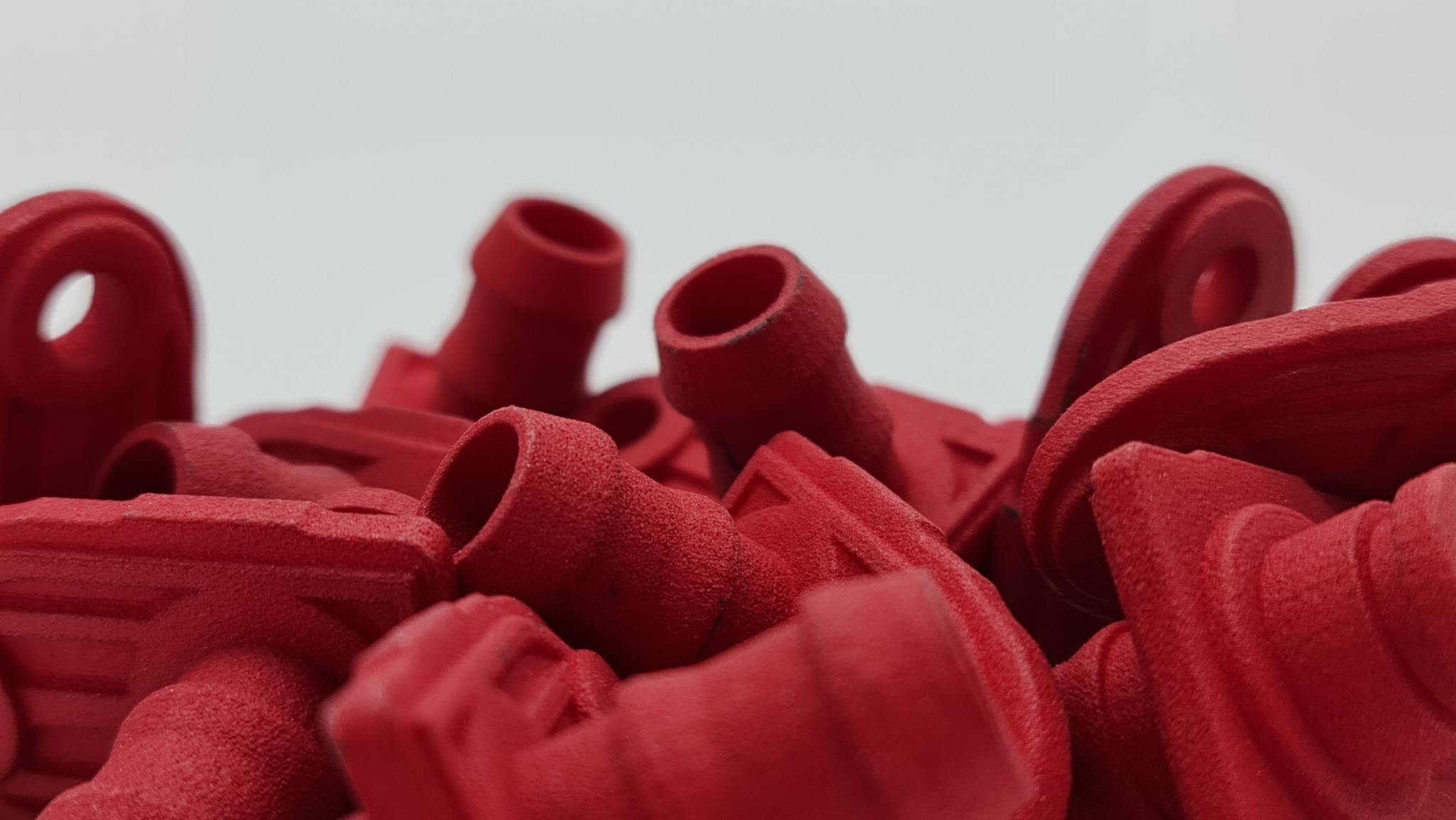 Czerwone elementy z druku 3D w Szczecinie, widoczne z bliska, ukazujące detale i strukturę materiału. Częściowo widoczne otwory i kształty.