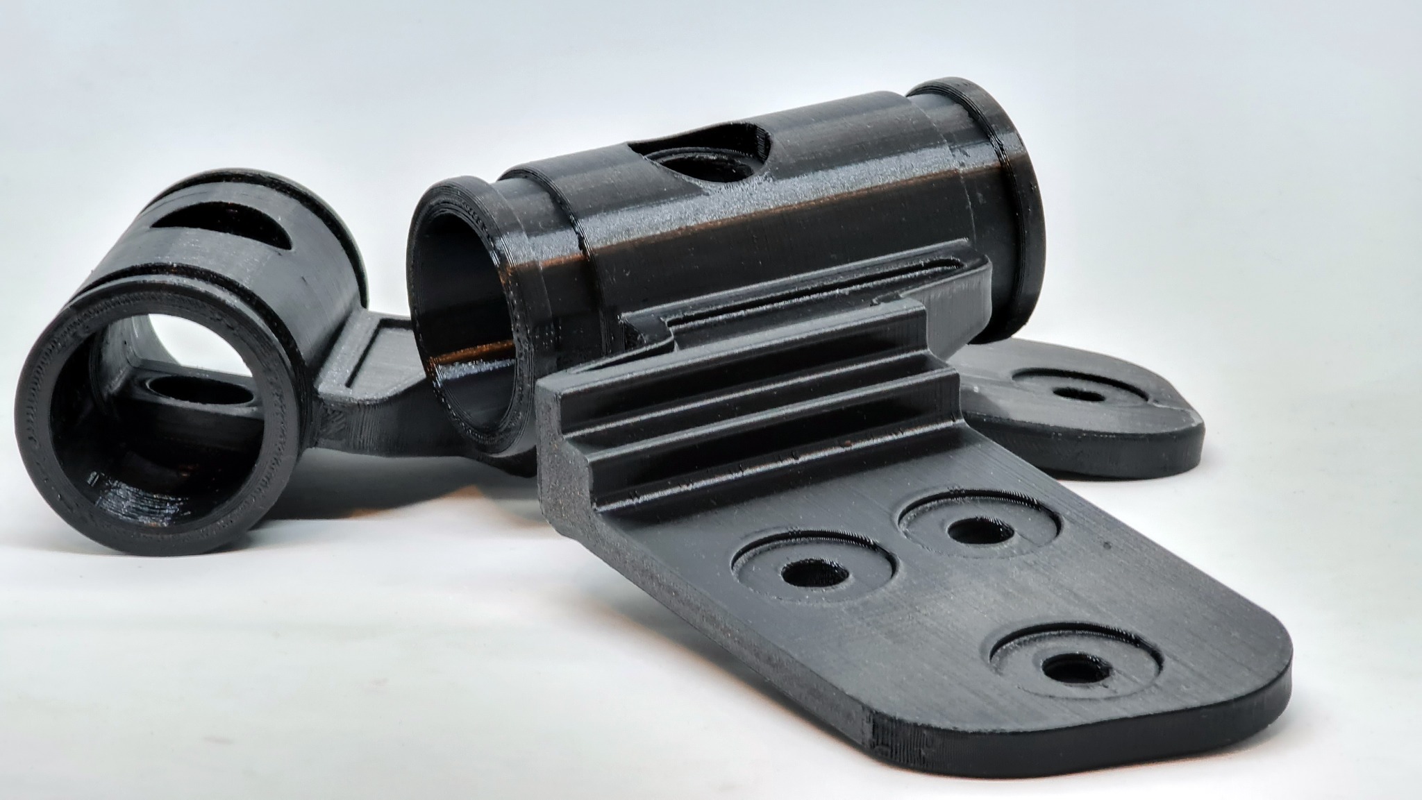 Precyzyjny, czarny element z tworzywa sztucznego z widoczną strukturą warstw, prawdopodobnie wykonany metodą addytywną. Widoczne otwory i żłobienia.