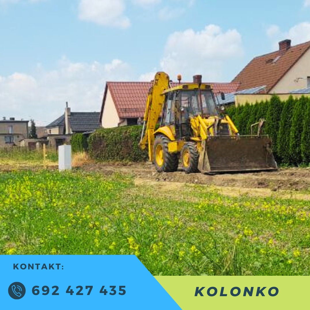 Żółta koparko-ładowarka na terenie budowy z widocznymi budynkami w tle i zielonymi krzewami. W dolnej części reklama firmy z numerem telefonu i nazwą.