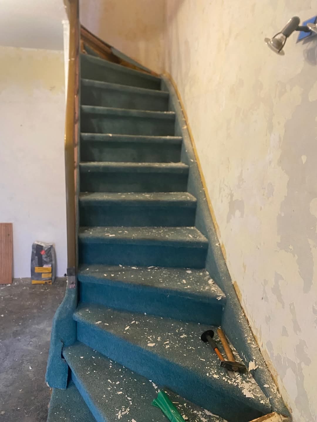 Demontaż starej wykładziny ze schodów w Storkow. Widoczne narzędzia i pozostałości po usuniętej wykładzinie. Przygotowanie do remontu schodów.