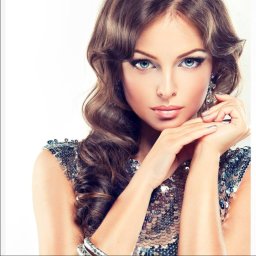 Gabinet Kosmetyki Laserowej i Stylizacji Paznokci Dorota Musidlak - Portret kobiety o niebieskich oczach, z błyszczącym makijażem, srebrnym manicure i falowanymi włosami, w cekinowej sukience i z kolczykami.