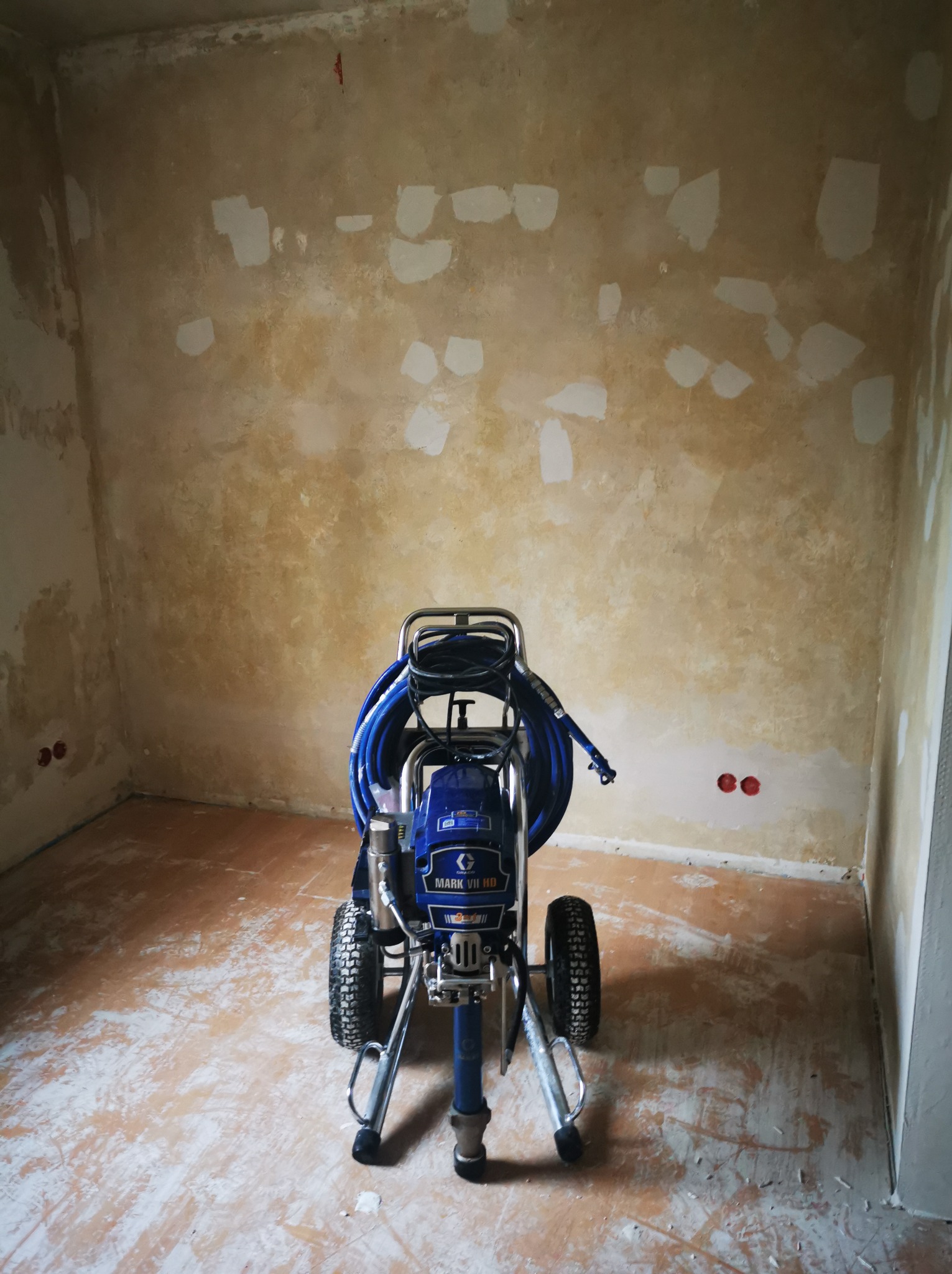 Agregat malarski Graco Mark VII HD w pokoju po szpachlowaniu w Toruniu. Przygotowanie do malowania natryskowego. Widoczne ślady po łataniu ścian.