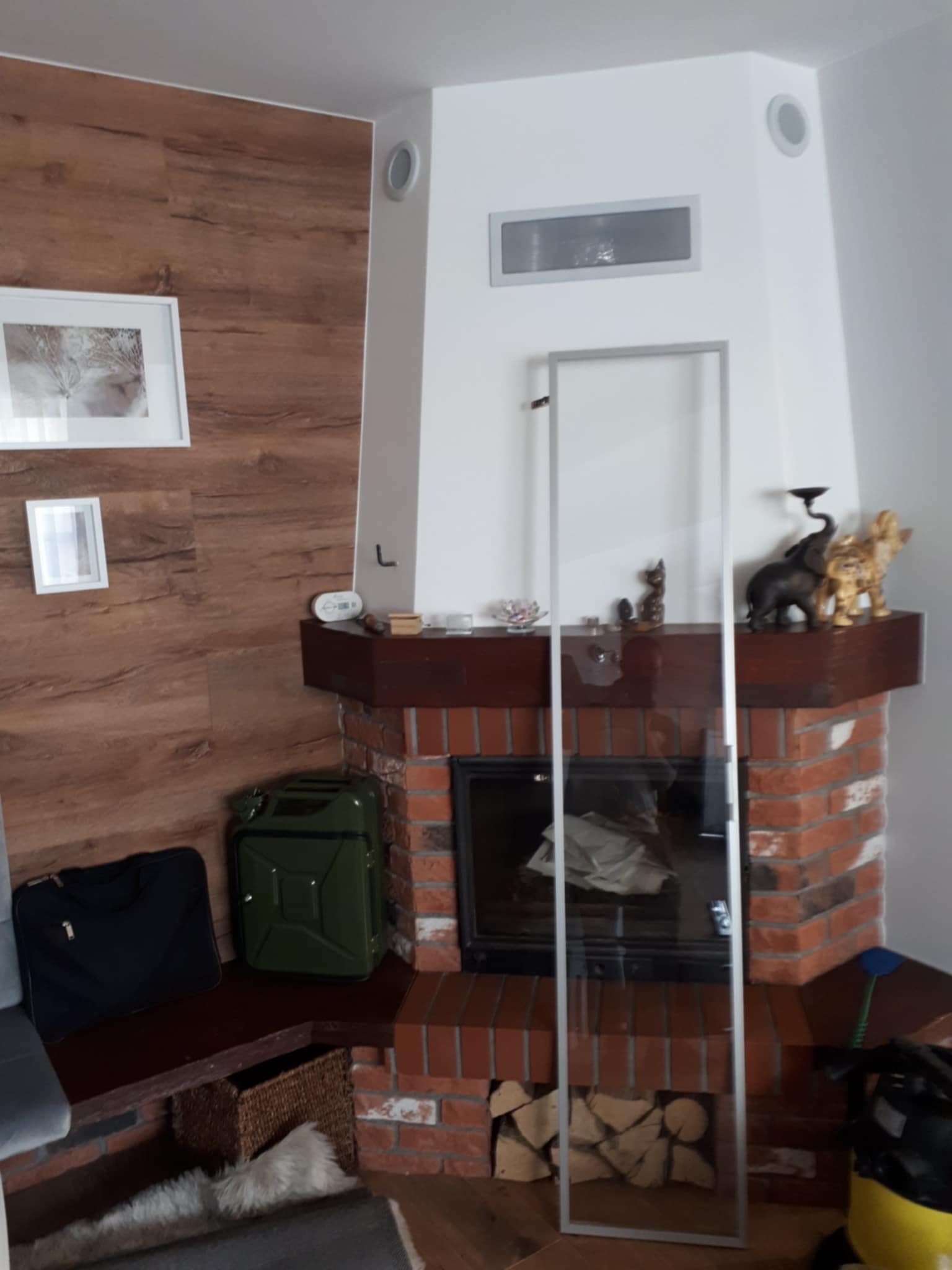 Ściana z panelami winylowymi imitującymi drewno, szpachlowane i pomalowane na biało ściany oraz sufit w pomieszczeniu z kominkiem.