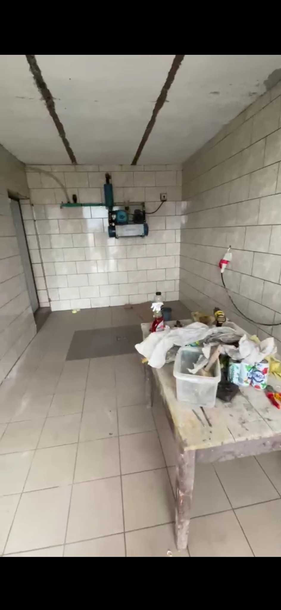 Łazienka w trakcie remontu w Baranowie: białe płytki na ścianach i podłodze, stół roboczy z narzędziami i materiałami budowlanymi, instalacja wodna na ścianie.