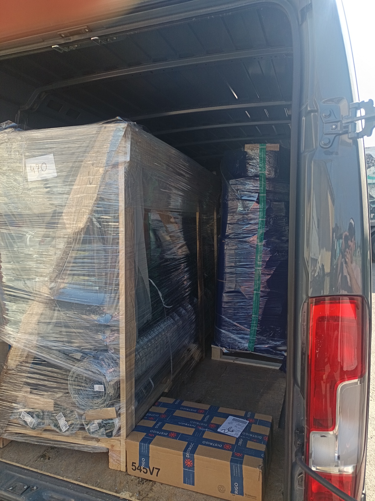 Wnętrze busa załadowane paletami z towarem, zabezpieczonym folią stretch, gotowym do transportu. Widoczne kartony z napisem DISTRIGO.