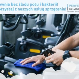 PERFECT CLEANING SPÓŁKA Z OGRANICZONĄ ODPOWIEDZIALNOŚCIĄ - Dezynfekcja sprzętu na siłowni: ręka z niebieską ściereczką czyści siedzisko maszyny, druga rozpyla środek dezynfekujący. W tle inne maszyny.