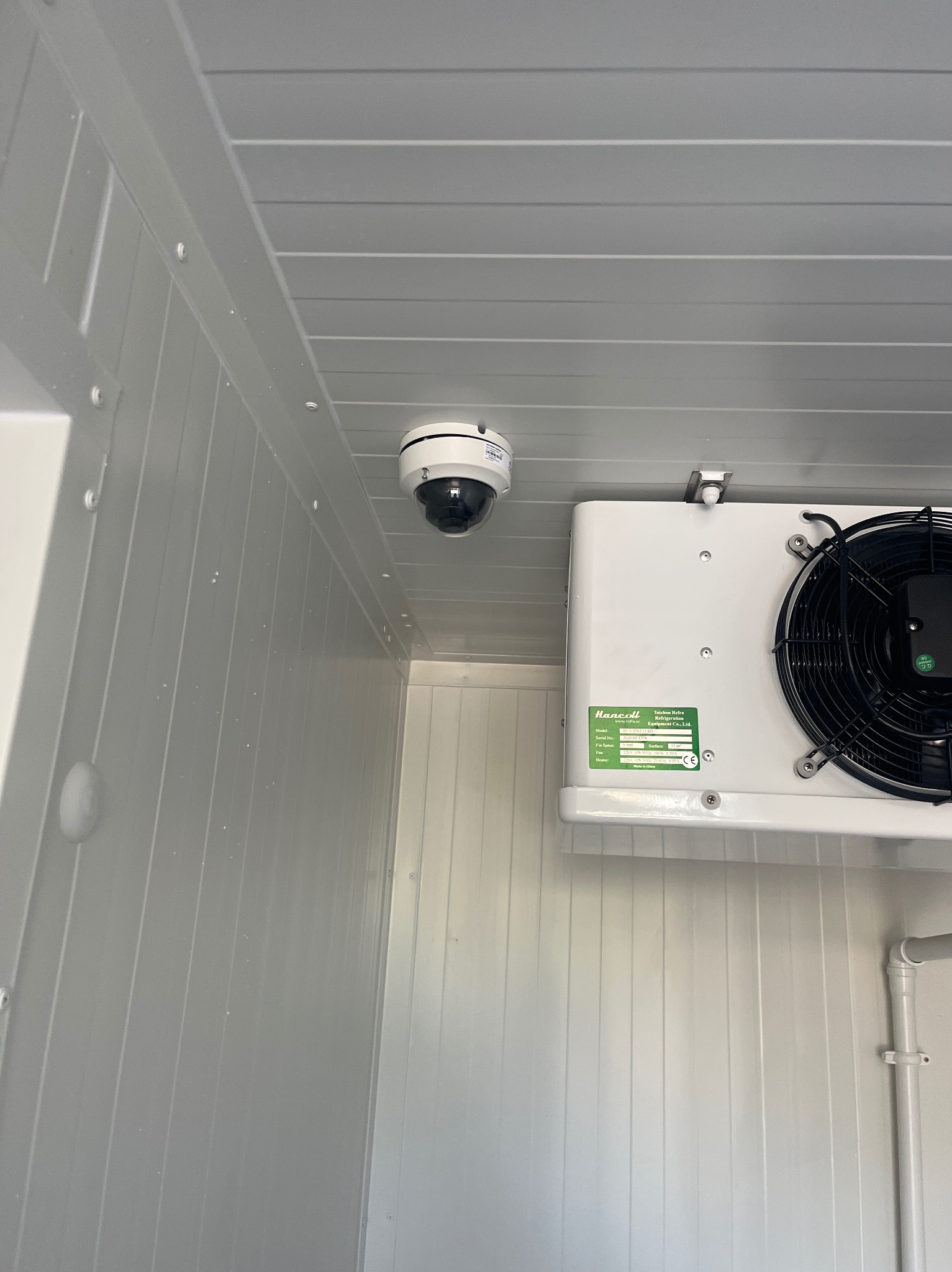 Wnętrze chłodni z zamontowaną kamerą kopułkową i agregatem chłodniczym Hancoll, widok z dołu na sufit i ścianę z paneli.