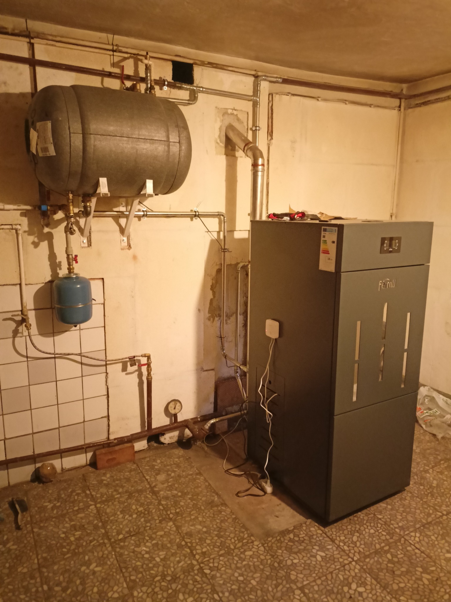 Szary piec Ferroli, zbiornik wyrównawczy i instalacja w kotłowni w Myszkowie. Rury miedziane prowadzone wzdłuż ściany, manometr na instalacji CO.