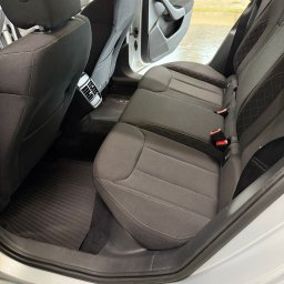 RENT-IPSUM TOMASZ ZIENTARA - Wnętrze auta po praniu tapicerki w Koszalinie: czyste, ciemne fotele z jasnym przeszyciem, gumowe dywaniki i otwarte drzwi. Detale wykończenia.