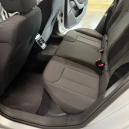 Wnętrze auta po praniu tapicerki w Koszalinie: czyste, ciemne fotele z jasnym przeszyciem, gumowe dywaniki i otwarte drzwi. Detale wykończenia.