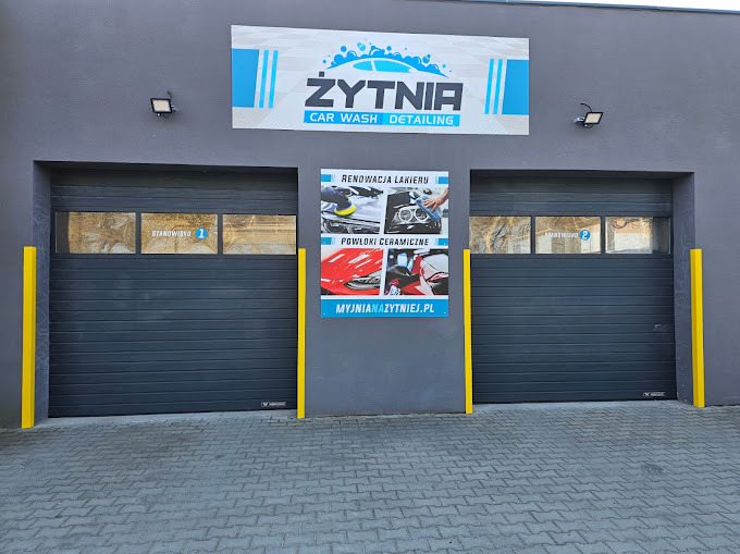 Fasada myjni Żytnia Car Wash Detailing z dwoma stanowiskami, plakat z renowacją lakieru i powłokami ceramicznymi. Żółte zabezpieczenia narożników.