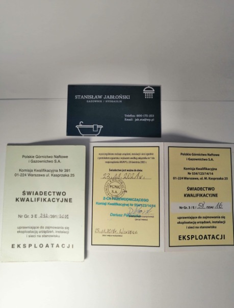 Wizytówka gazownika Stanisława Jabłońskiego z certyfikatami kwalifikacyjnymi PGNIG, eksploatacja urządzeń, instalacji i sieci. Jasne tło, bliski kadr.