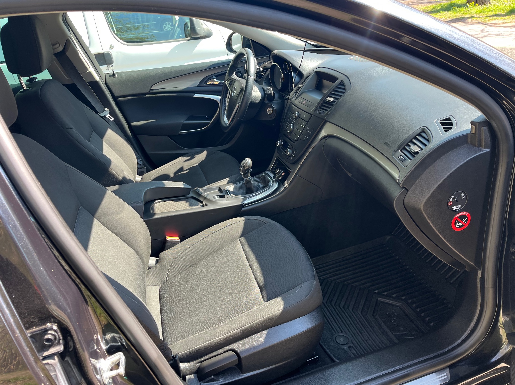 Wnętrze czarnego samochodu osobowego z widocznymi przednimi fotelami, deską rozdzielczą i kierownicą, oświetlone naturalnym światłem słonecznym.