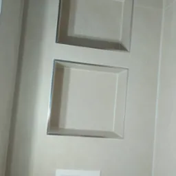 Wykończona łazienka: beżowe płytki z wnękami z chromowanymi ramkami oraz podtynkowy panel WC z dwoma przyciskami. Minimalistyczny design.