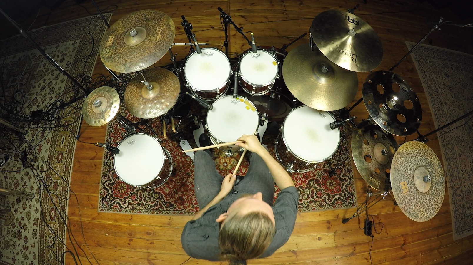 Perkusista z góry: zestaw perkusyjny z talerzami Byzance, mikrofonami i dywanami w tle. Widok z lotu ptaka na muzyka z pałeczkami w rękach, gotowego do gry.