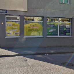 BIURO NIERUCHOMOŚCI GREATHOUSE - Fasada biura nieruchomości z oknami oklejonymi reklamami usług: sprzedaż, kupno, kredyty, ubezpieczenia, projektowanie wnętrz, home staging, geodeta, architekt, radca prawny.