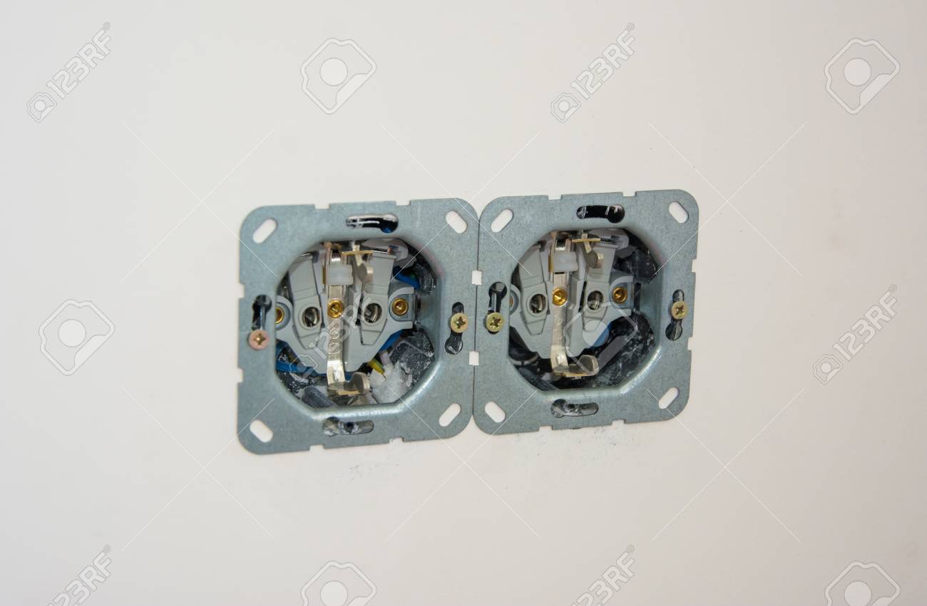 Dwa gniazdka elektryczne podwójne, zamontowane w ścianie, widoczne wewnętrzne elementy i przewody, przygotowane do dalszego montażu.