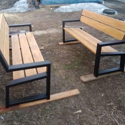 Energo Usługi Spawalnicze GRZEGORZ GODULA - Dwie ławki z drewnianym siedziskiem i czarną, metalową konstrukcją, ustawione na drewnianych deskach na zewnątrz. W tle resztki śniegu.