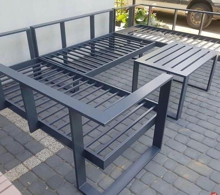 Metalowy stelaż sofy i stolika na tarasie, konstrukcja spawana z profili, pomalowana na szaro, widoczne detale łączeń i regularny układ szczebli.