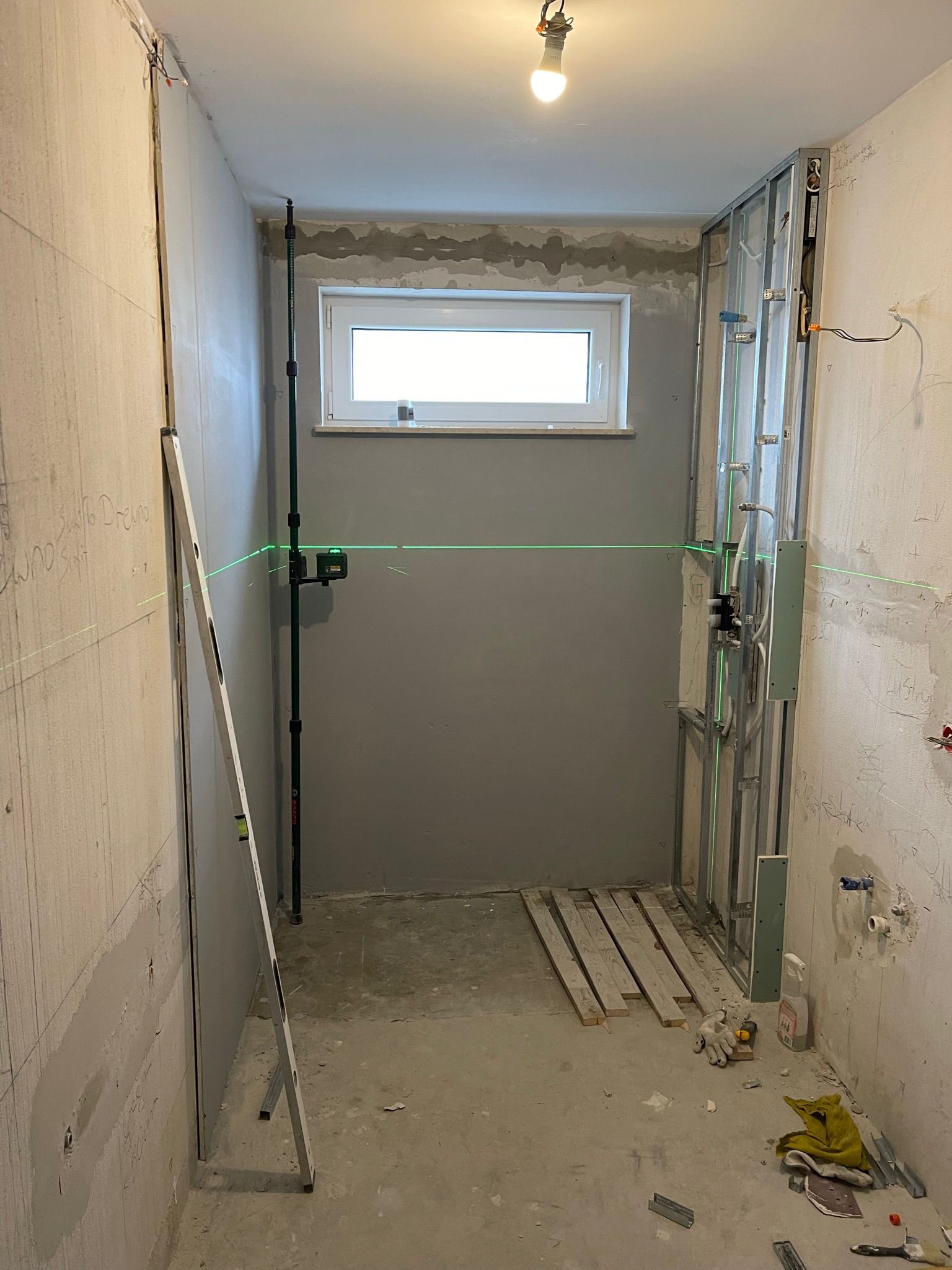 Łazienka w trakcie remontu: widoczne profile, poziomica laserowa, przygotowane ściany, okno. Etap prac przed wykończeniem, surowy stan.