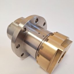 PRZEDSIĘBIORSTWO PRODUKCYJNO - USŁUGOWE WAMECH SPÓŁKA Z OGRANICZONĄ ODPOWIEDZIALNOŚCIĄ - Precyzyjnie wykonany, metalowy element z brązowymi i srebrnymi detalami. Widoczne otwory i gwinty, świadczące o zaawansowanej obróbce.