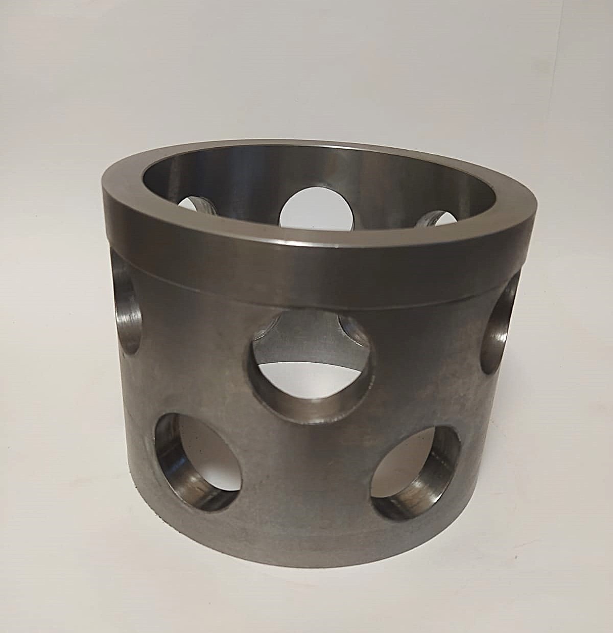 Metalowy cylinder z otworami, precyzyjnie wykonany w Krakowie. Szlifowana powierzchnia, widoczne ślady obróbki. Detal z bliska, idealny do zastosowań przemysłowych.