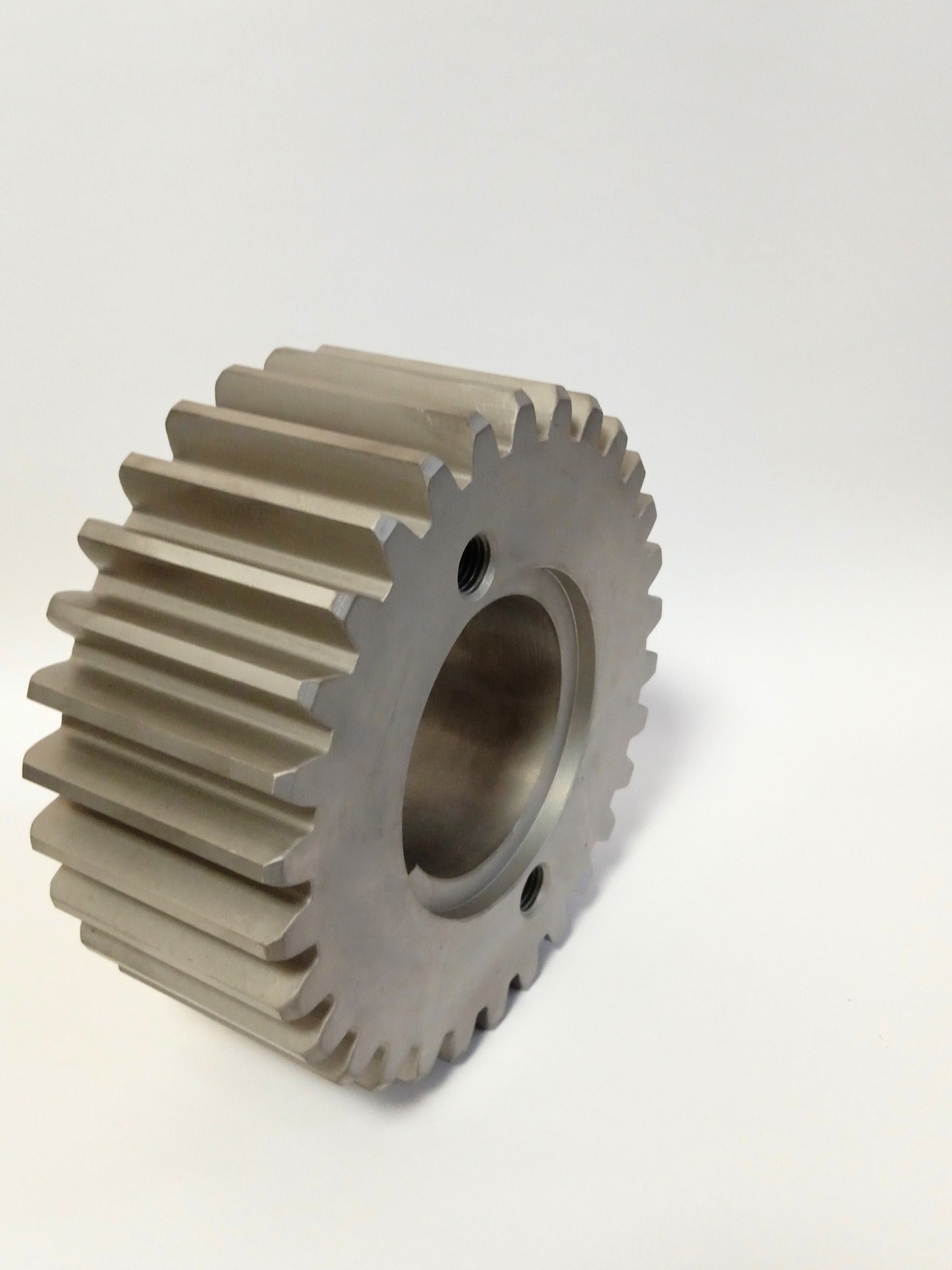 Precyzyjnie wykonane koło zębate ze stali z otworem i dwoma otworami montażowymi, sfotografowane na białym tle.