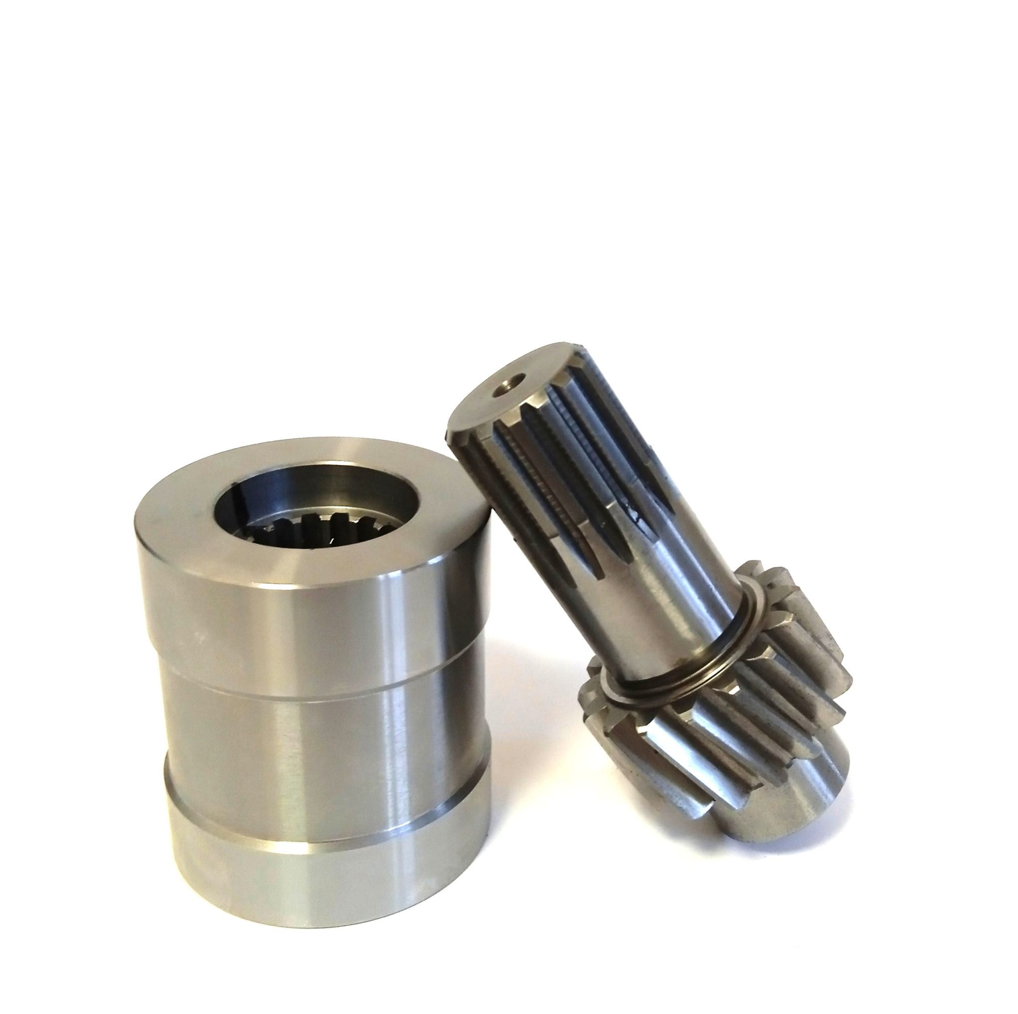 Precyzyjnie wykonane, metalowe elementy: tuleja z zębatym wnętrzem i wałek z zębami, leżące ukośnie na białym tle. Detal z bliska, ukazujący dokładność obróbki.