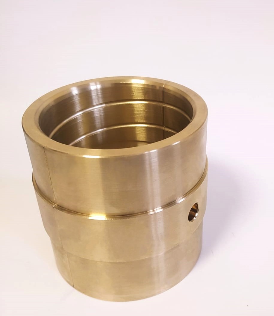 Mosiężna tuleja cylindryczna z otworem, precyzyjnie obrobiona, widoczna na białym tle. Gładka powierzchnia, detale obróbki. Obróbka Metali.