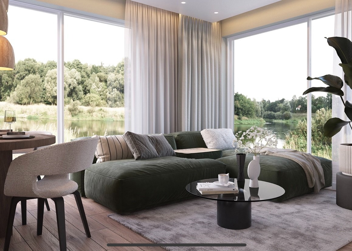 Stylowy salon z zieloną sofą modułową, okrągłym stolikiem kawowym i widokiem na rzekę przez duże okna. Krzesło z boucle i drewniany stół jadalny w lewym rogu.