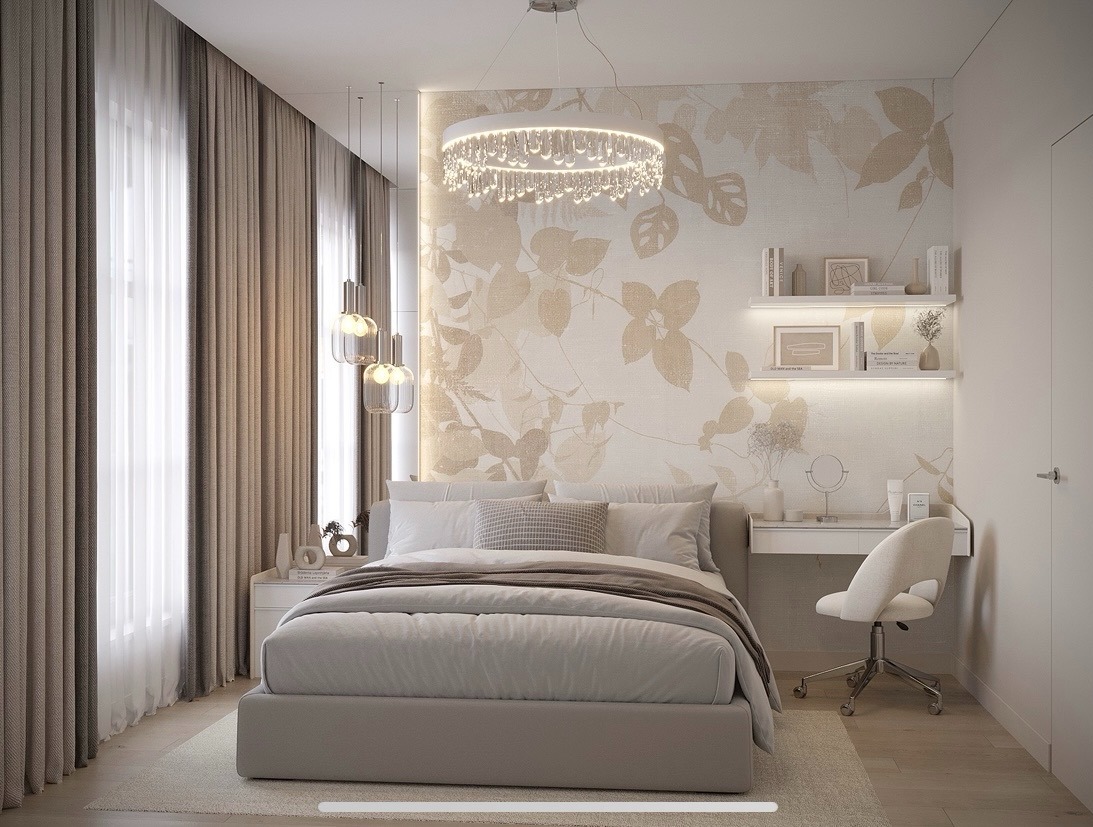 Neutralna sypialnia z łóżkiem typu king-size, biurkiem i krzesłem, oświetlona dekoracyjnym żyrandolem i lampami wiszącymi. Na ścianie tapeta w motywy roślinne.
