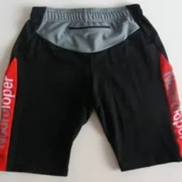 Czarne spodenki sportowe z czerwonym nadrukiem 'Nordloper' po bokach i szarym karczkiem z tyłu, widoczne z bliska na białym tle. Kieszonka na zamek z tyłu.