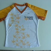 Biała koszulka z krótkim rękawem i żółtymi wstawkami na ramionach. Na koszulce nadruk z motywem ważek i napisem 'binnen Breda'. Widok z góry, na płaskim tle.