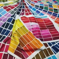 Wzornik kolorów na tkaninie z wyraźną gradacją barw, ułożony artystycznie, prezentujący szeroką paletę odcieni i ich numeryczne oznaczenia.