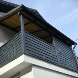 Ciemnoszara, pozioma balustrada zadaszonego balkonu z drewnianym sufitem, widok z dołu, słoneczny dzień, nowoczesny design.