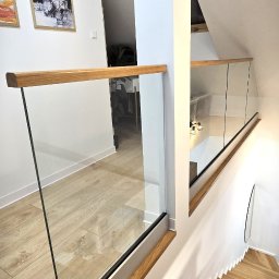 Bombowe Konstrukcje - Szklana balustrada z drewnianym wykończeniem na schodach w nowoczesnym wnętrzu. Widok z góry na drewniane stopnie i eleganckie, minimalistyczne wykończenie.