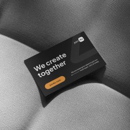 BYGÓRA DESIGN Bartosz Góra - Czarna wizytówka firmy Join4u z hasłem 'We create together' leży na szarym, teksturowanym tle. Tekst jest biały, a logo firmy jest pomarańczowe.