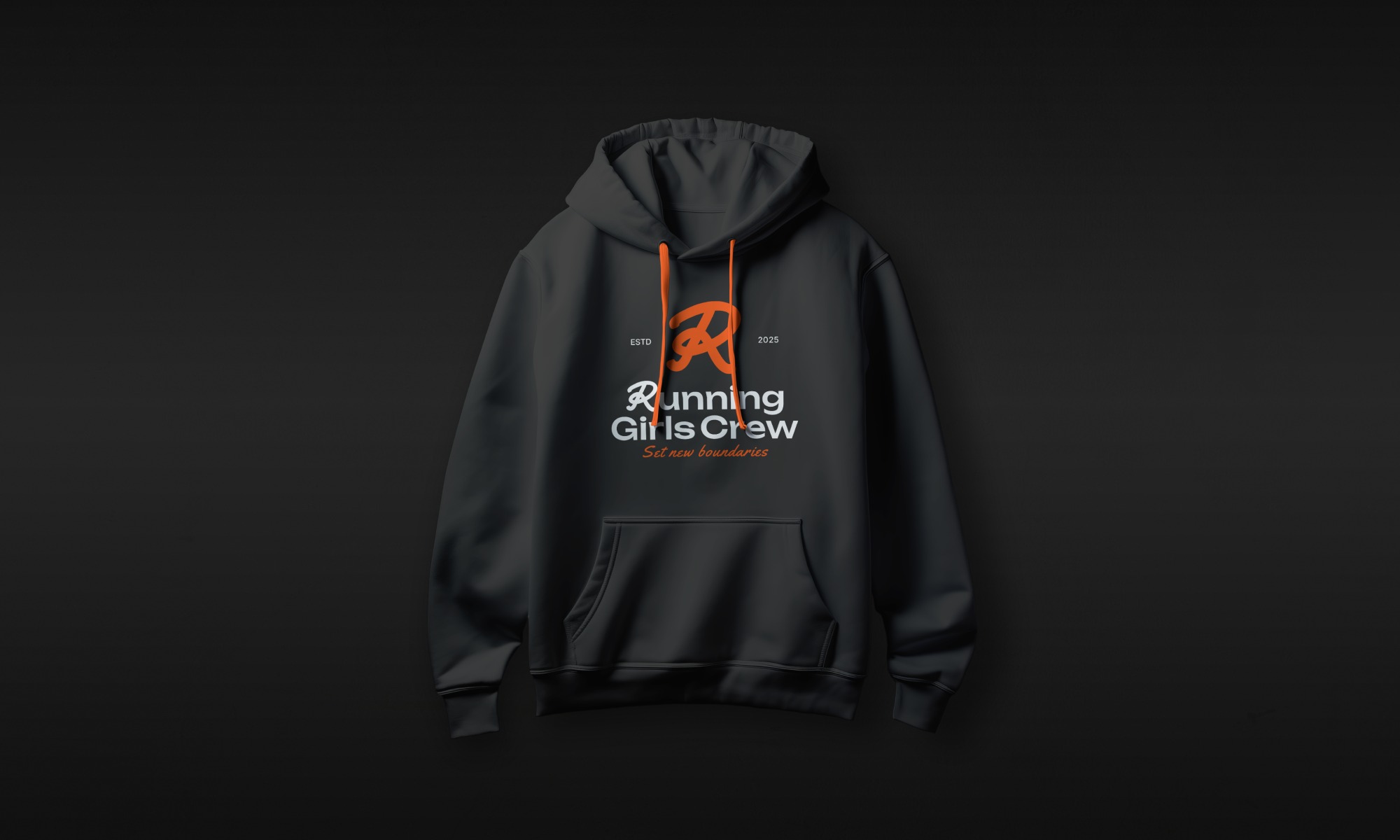 Czarna bluza z kapturem, z pomarańczowym logo 'Running Girls Crew' i napisem 'Set new boundaries' na ciemnoszarym tle. Prezentacja nadruku na odzieży.
