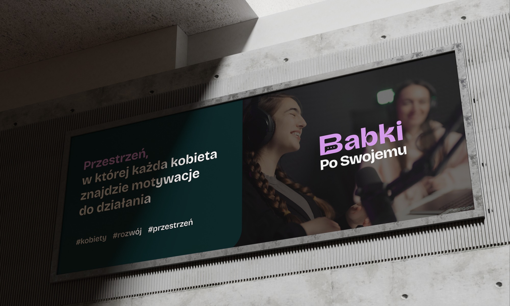 Billboard z hasłem motywacyjnym dla kobiet. Grafika w odcieniach zieleni i fioletu, przedstawia profil kobiety w słuchawkach oraz fragment studia nagraniowego.