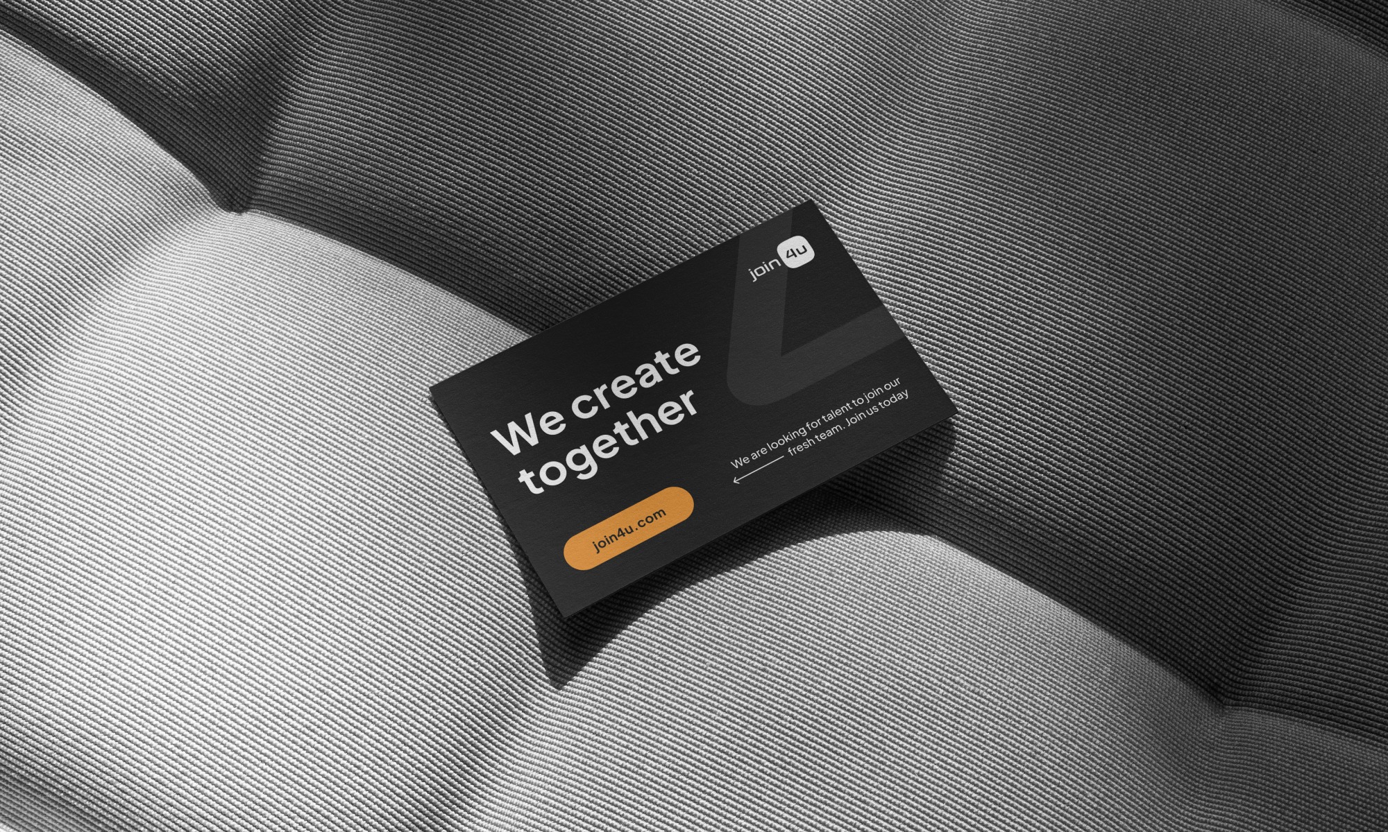 Czarna wizytówka firmy Join4u z hasłem 'We create together' leży na szarym, teksturowanym tle. Tekst jest biały, a logo firmy jest pomarańczowe.