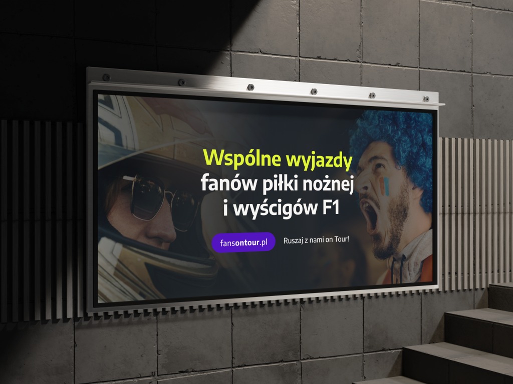 Billboard reklamujący wspólne wyjazdy dla fanów piłki nożnej i F1, z wizerunkami kibica i kierowcy wyścigowego. Widoczny adres strony internetowej.