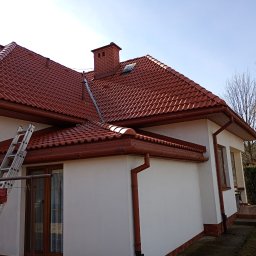 Mycie ciśnieniowe - Dom z nowym, czerwonym dachem z dachówki ceramicznej i rynnami w tym samym kolorze. Przystawiona drabina sugeruje prace dekarskie.